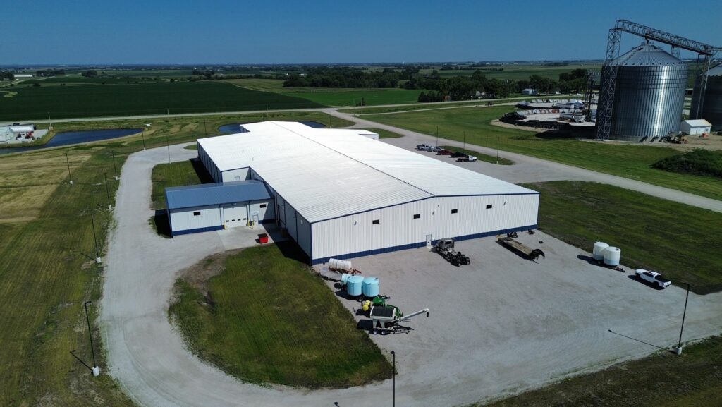Lager fertilizer manufacturing facility in Iowa shows truck traffic pattern with green soybean field and grain bin
