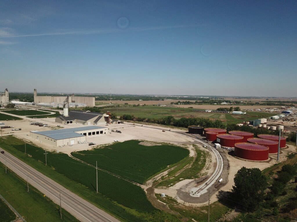 overhead view of a liquid fertilizer plant and tanks with 44,000 ton dry plant food warehouse in background