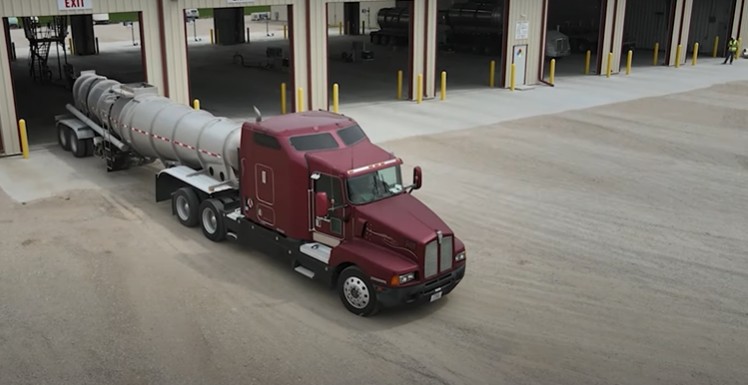 Fertilizer truck taking crop nutrients to the farm from a 24/7 agricultural chemistry receiving and Loading building