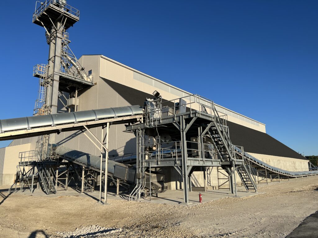 Bulk storage facility and conveying equipment located on a river for barge receiving