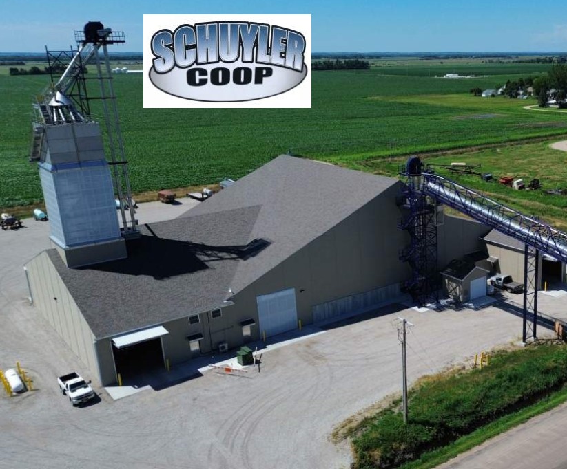 Schuyler Dry fertilizer storage warehouse with fertilizer conveyor into the building with a blend tower and green farm crop fields in the background
