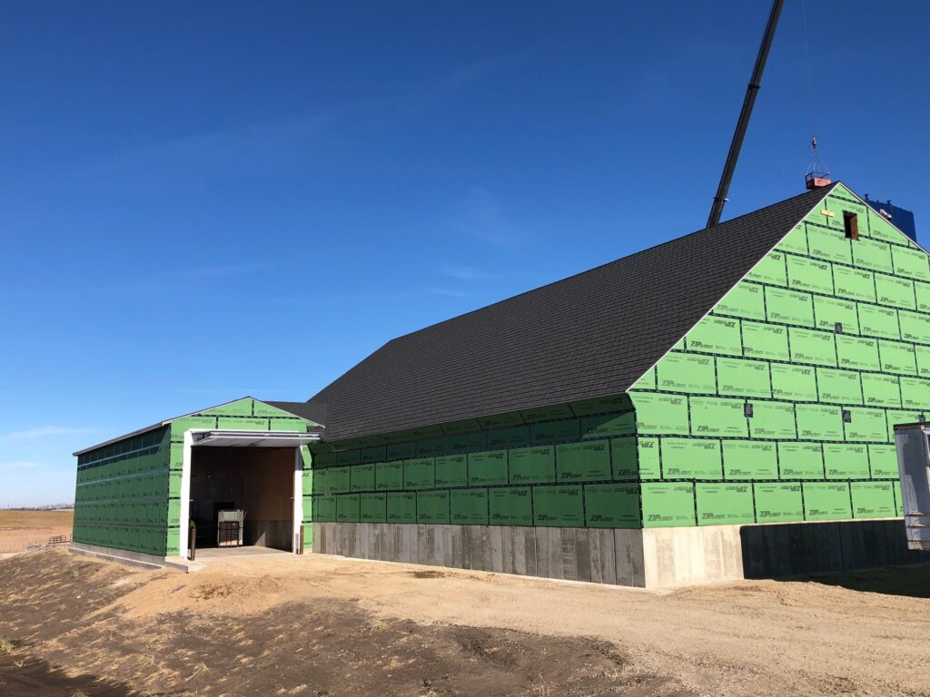 New fertilizer building with 50 year warranty metal roofing shingle and zip board sheathing next to covered fertilizer receiving bay