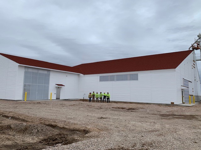 red metal roof shingles on a new white fertilizer building with stueve construction workers