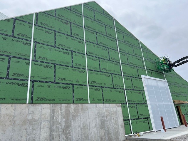 Green zip board coating on end wall of dry fertilizer structure with bi-fold door and man lift