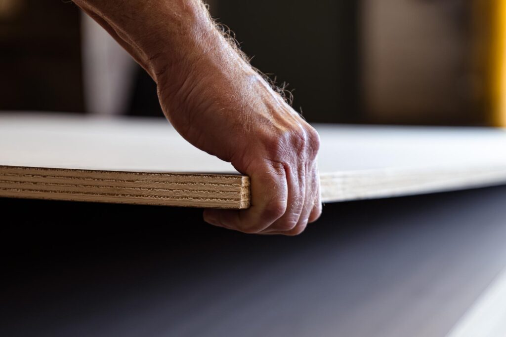 man lifting plywood while building fertilizer storage bin